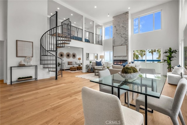 200 S Catalina Ave Unit 403, Redondo Beach, CA 90277 - dining area featuring a towering ceiling, stairs, a fireplace, recessed lighting, and light wood-style flooring