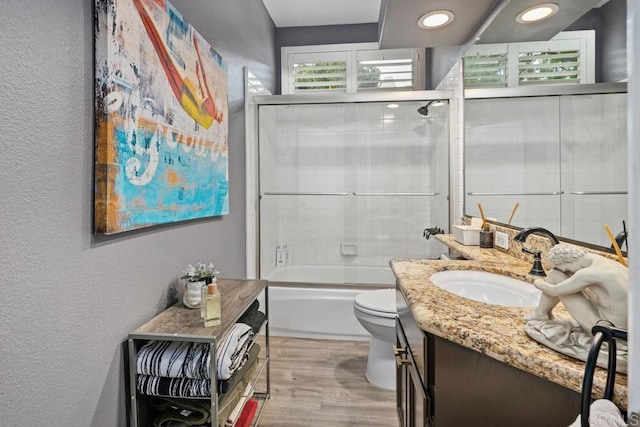 4520 Tarantella Ln, San Diego, CA 92130 - full bathroom with a textured wall, vanity, toilet, wood finished floors, and bath / shower combo with glass door