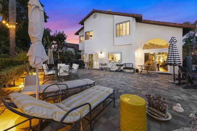 4520 Tarantella Ln, San Diego, CA 92130 - back of property at dusk with outdoor dining space, a patio, and stucco siding