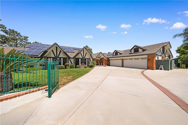 2360 Oakleaf Canyon Rd, Walnut, CA 91789 - tudor-style house with concrete driveway, roof mounted solar panels, an attached garage, and a gate