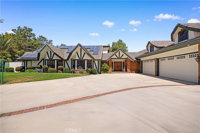 2360 Oakleaf Canyon Rd, Walnut, CA 91789 - tudor-style house with driveway, stucco siding, solar panels, a front lawn, and a tile roof