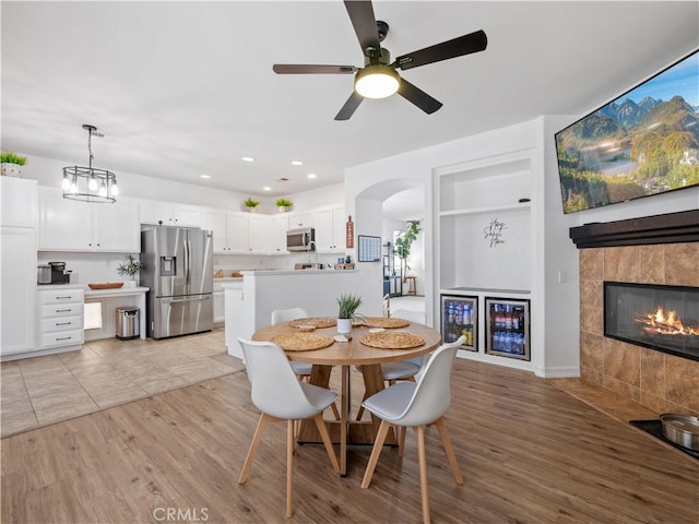 15631 Moccasin Ct, Victorville, CA 92394 - dining space featuring arched walkways, light wood-type flooring, recessed lighting, a ceiling fan, and a tiled fireplace