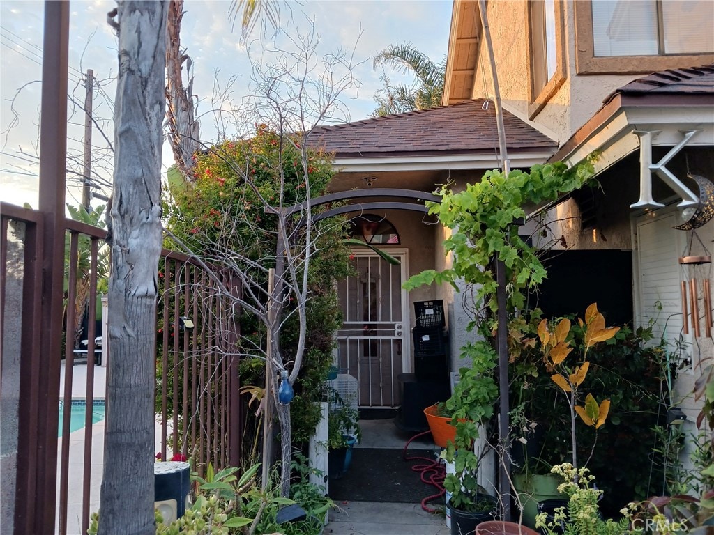 726 W Wilson St Unit K, Costa Mesa, CA 92627 - view of exterior entry featuring stucco siding, an outdoor pool, and a shingled roof