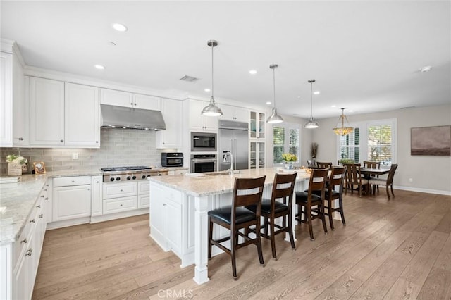 108 Sideways, Irvine, CA 92618 - kitchen featuring under cabinet range hood, built in appliances, light wood finished floors, backsplash, and recessed lighting