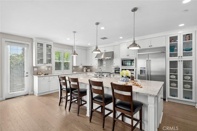 108 Sideways, Irvine, CA 92618 - kitchen with built in appliances, under cabinet range hood, white cabinets, light wood-type flooring, and tasteful backsplash