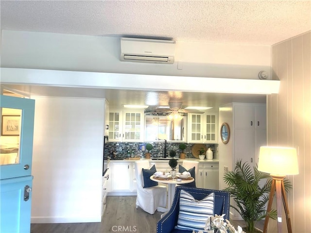 1411 Pelham Rd Unit 664H, Seal Beach, CA 90740 - kitchen featuring a wall mounted air conditioner, a textured ceiling, white cabinets, light wood-style flooring, and tasteful backsplash