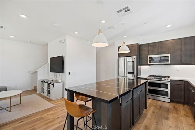 7436 Royal St, Buena Park, CA 90620 - kitchen with stainless steel appliances, light wood finished floors, dark brown cabinets, pendant lighting, and recessed lighting