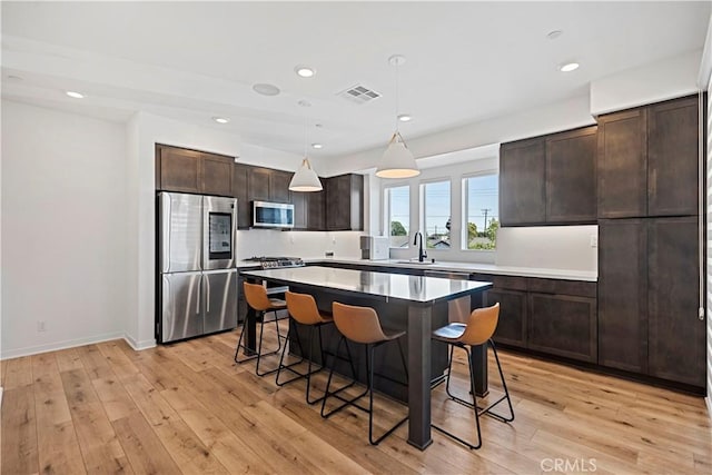 7436 Royal St, Buena Park, CA 90620 - kitchen featuring stainless steel appliances, a breakfast bar area, dark brown cabinetry, light wood-type flooring, and a center island