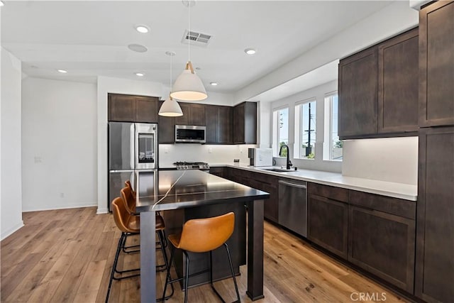 7436 Royal St, Buena Park, CA 90620 - kitchen featuring stainless steel appliances, a sink, a kitchen breakfast bar, dark brown cabinetry, and light wood finished floors
