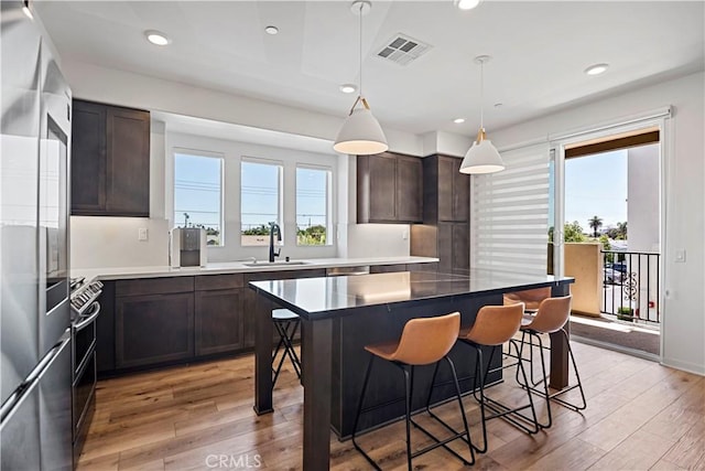 7436 Royal St, Buena Park, CA 90620 - kitchen with a sink, dark brown cabinetry, light wood-style flooring, a breakfast bar, and recessed lighting