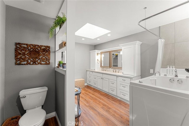 1270 Belle Rd, Calimesa, CA 92320 - full bath featuring a skylight, a bathtub, wood finished floors, vanity, and toilet