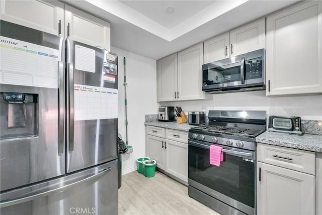 1264 N Mulberry Ave, Rialto, CA 92376 - kitchen featuring appliances with stainless steel finishes, light wood finished floors, light stone counters, and white cabinetry