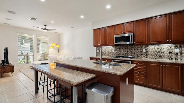2510 Aperture Cir, San Diego, CA 92108 - kitchen featuring stainless steel microwave, light tile patterned flooring, backsplash, an island with sink, and a sink