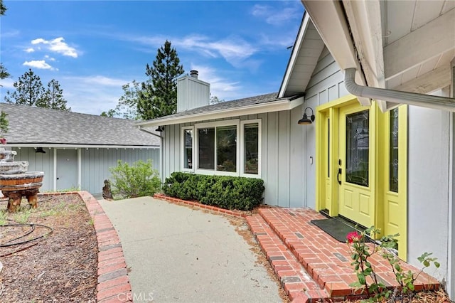 30396 Live Oak Dr, Running Springs, CA 92382 - view of exterior entry featuring board and batten siding, a chimney, a patio, and roof with shingles