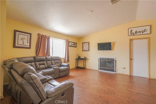 22780 Shawnee Rd, Apple Valley, CA 92308 - living room featuring wood finished floors, vaulted ceiling, a textured ceiling, a fireplace, and baseboards