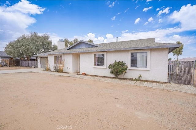 22780 Shawnee Rd, Apple Valley, CA 92308 - ranch-style home with concrete driveway, an attached garage, a chimney, stucco siding, and roof with shingles
