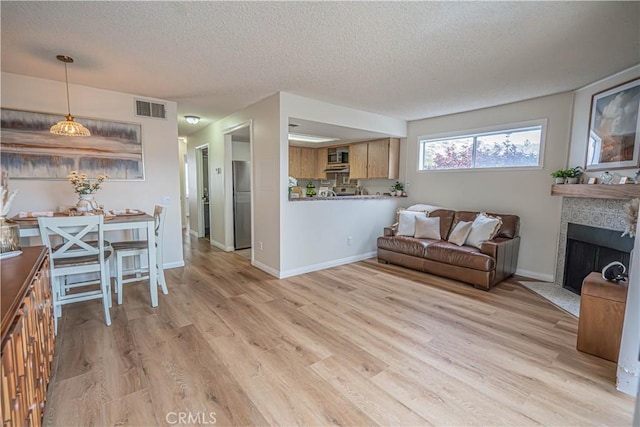 18209 Sierra Unit 45, Canyon Country, CA 91351 - living room with a textured ceiling, light wood-type flooring, a fireplace with flush hearth, and baseboards