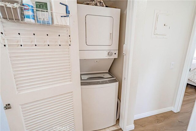 18209 Sierra Unit 45, Canyon Country, CA 91351 - laundry room featuring stacked washer / dryer, wood finished floors, and baseboards