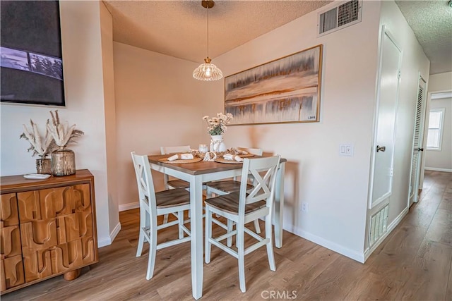 18209 Sierra Unit 45, Canyon Country, CA 91351 - dining space featuring a textured ceiling, wood finished floors, and baseboards
