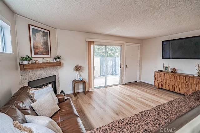 18209 Sierra Unit 45, Canyon Country, CA 91351 - living area featuring wood finished floors, a textured ceiling, baseboards, and a tile fireplace