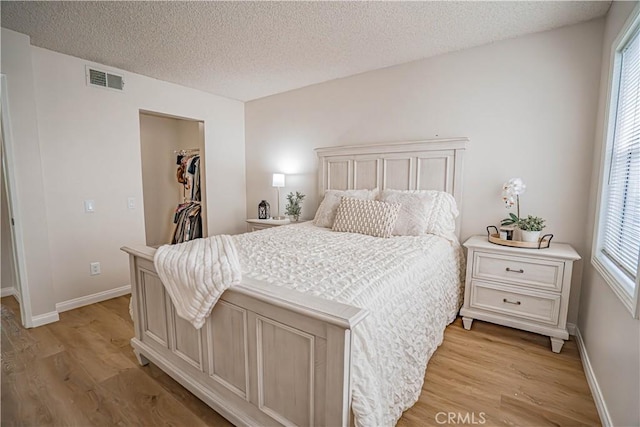 18209 Sierra Unit 45, Canyon Country, CA 91351 - bedroom with light wood finished floors, multiple windows, a walk in closet, and a textured ceiling