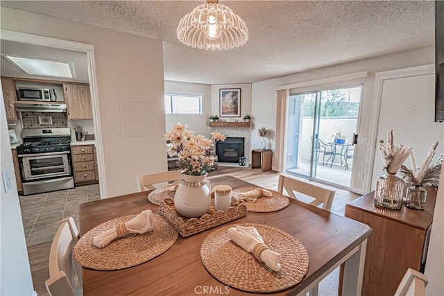 18209 Sierra Unit 45, Canyon Country, CA 91351 - dining area with a glass covered fireplace, healthy amount of natural light, a chandelier, and a textured ceiling