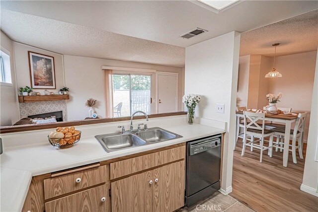 18209 Sierra Unit 45, Canyon Country, CA 91351 - kitchen with black dishwasher, a sink, a textured ceiling, light countertops, and a glass covered fireplace