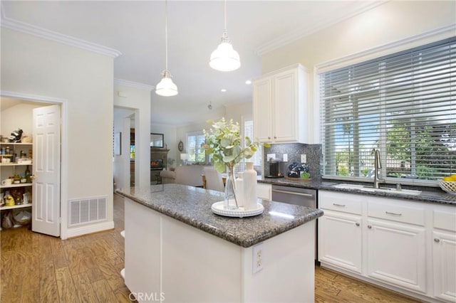 15 Beacon, Ladera Ranch, CA 92694 - kitchen with a sink, decorative backsplash, crown molding, white cabinets, and light wood-type flooring