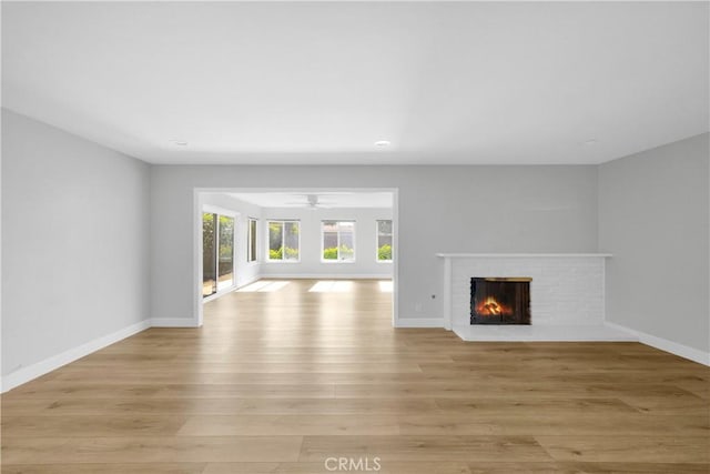 12151 Reagan St, Los Alamitos, CA 90720 - unfurnished living room with a brick fireplace, light wood-style flooring, a ceiling fan, baseboards, and recessed lighting