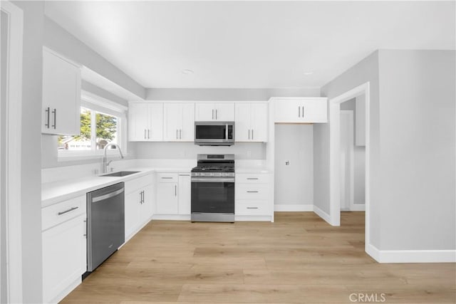 12151 Reagan St, Los Alamitos, CA 90720 - kitchen featuring stainless steel appliances, a sink, light countertops, white cabinets, and baseboards