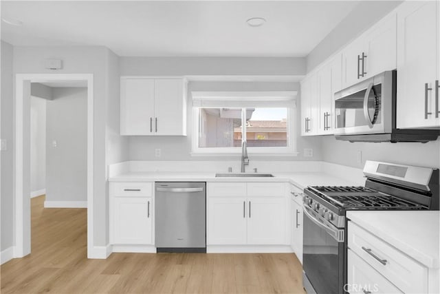 12151 Reagan St, Los Alamitos, CA 90720 - kitchen with stainless steel appliances, a sink, light wood-style floors, white cabinetry, and light countertops