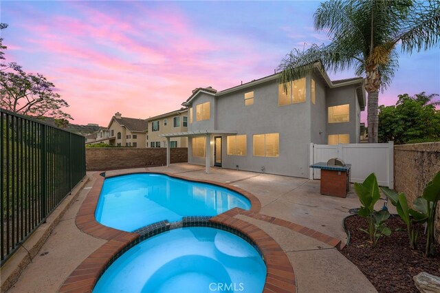 16209 Eagleridge Ct, La Mirada, CA 90638 - pool at dusk with a pool with connected hot tub, a fenced backyard, and a patio area
