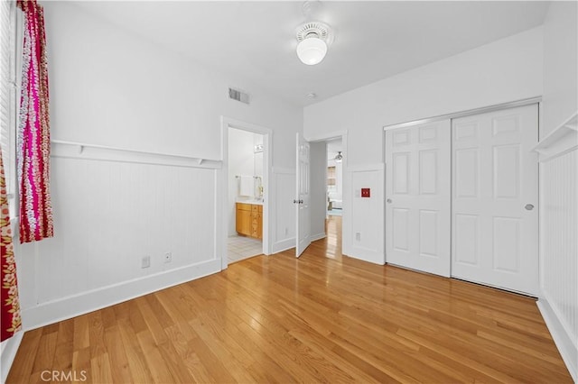 26 Middleton, Irvine, CA 92620 - unfurnished bedroom featuring light wood-type flooring, a wainscoted wall, a closet, ensuite bath, and a decorative wall