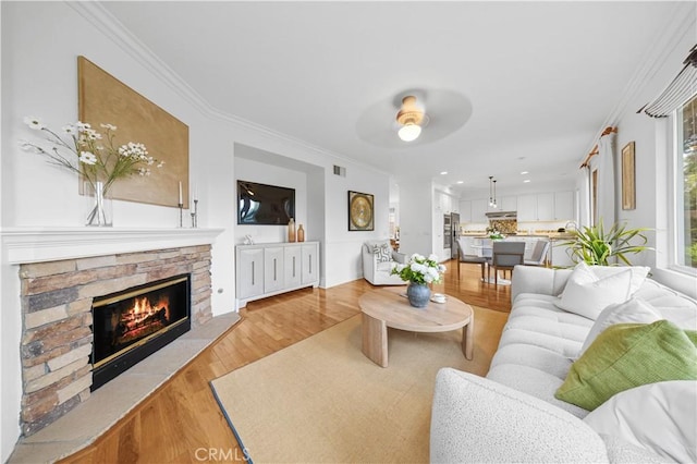 26 Middleton, Irvine, CA 92620 - living room with a ceiling fan, a stone fireplace, light wood-style floors, ornamental molding, and recessed lighting