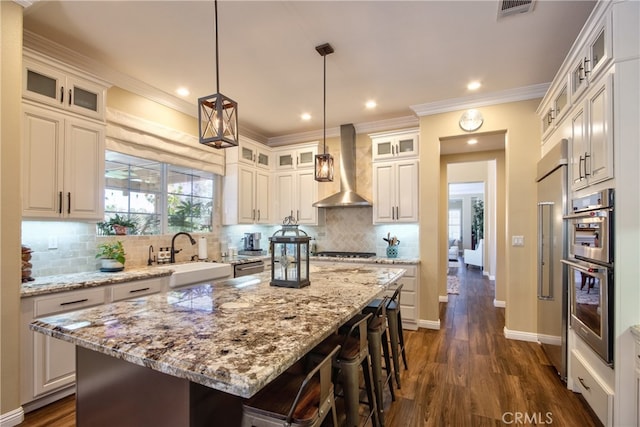 42926 Joshua Tree Ct, Murrieta, CA 92562 - kitchen with wall chimney exhaust hood, a sink, a kitchen bar, a center island, and dark wood-style flooring