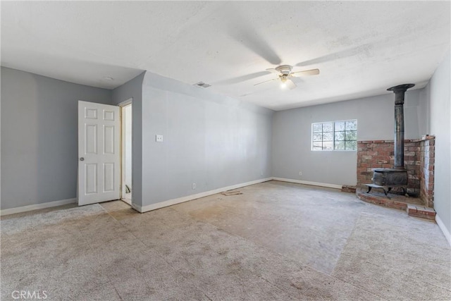 35921 80th St E, Littlerock, CA 93543 - unfurnished living room with ceiling fan, a wood stove, baseboards, and carpet floors