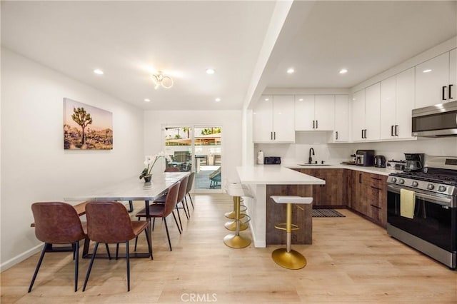 589 S Mountain View Dr, Palm Springs, CA 92264 - kitchen featuring appliances with stainless steel finishes, a sink, a kitchen bar, modern cabinets, and a peninsula