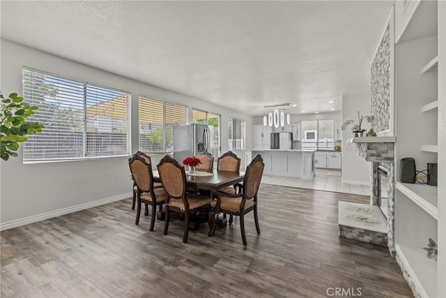 27051 Featherhill Dr, Corona, CA 92883 - dining space featuring light wood-style floors, baseboards, a chandelier, and a stone fireplace