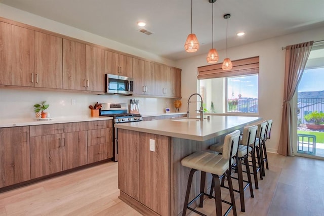 35140 Bergamot, Fallbrook, CA 92028 - kitchen with stainless steel appliances, light wood-type flooring, a breakfast bar area, a kitchen island with sink, and light countertops