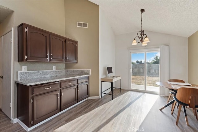 2433 N Knoll Ave, Fresno, CA 93722 - kitchen with wood finished floors, lofted ceiling, a chandelier, dark brown cabinets, and a textured ceiling