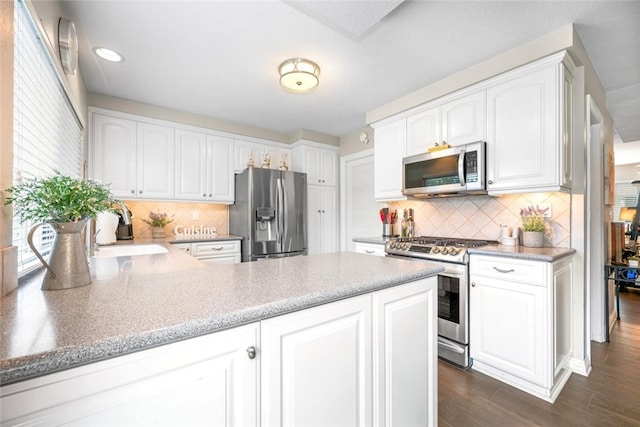 6898 Breton Way, Cypress, CA 90630 - kitchen featuring appliances with stainless steel finishes, a peninsula, white cabinets, dark wood-style floors, and decorative backsplash
