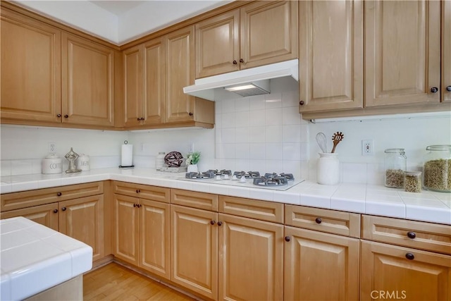 30 Oakhurst Rd, Irvine, CA 92620 - kitchen with under cabinet range hood, white gas stovetop, tile countertops, decorative backsplash, and light wood-style flooring