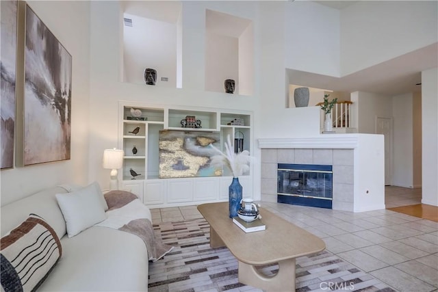 30 Oakhurst Rd, Irvine, CA 92620 - living area featuring a high ceiling, built in shelves, tile patterned flooring, a tile fireplace, and baseboards