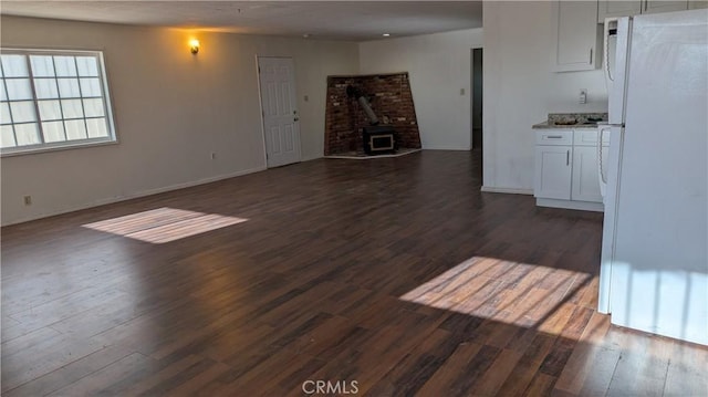 6445 Pony Rd, Johnson Valley, CA 92285 - unfurnished living room featuring a wood stove, dark wood-type flooring, and baseboards