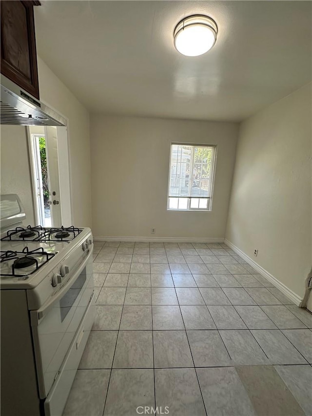 942 E 6th St, Pomona, CA 91766 - kitchen with white gas range oven, light tile patterned flooring, under cabinet range hood, and dark brown cabinetry