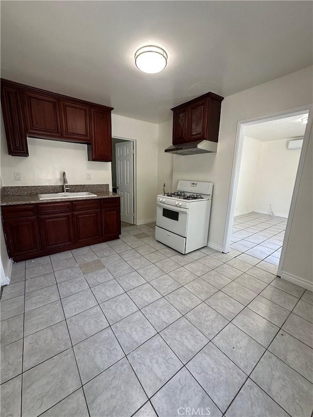 942 E 6th St, Pomona, CA 91766 - kitchen with gas range gas stove, under cabinet range hood, light tile patterned flooring, and dark stone counters