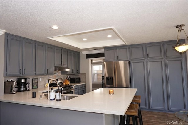 2622 Presidio Ln, Corona, CA 92879 - kitchen with appliances with stainless steel finishes, under cabinet range hood, a peninsula, a raised ceiling, and light countertops