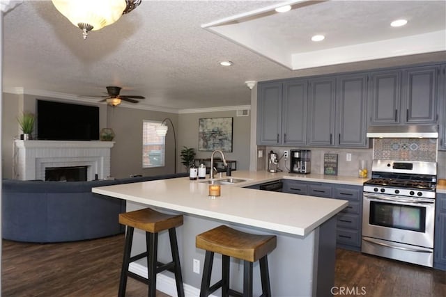 2622 Presidio Ln, Corona, CA 92879 - kitchen with stainless steel range with gas cooktop, under cabinet range hood, a peninsula, light countertops, and a ceiling fan