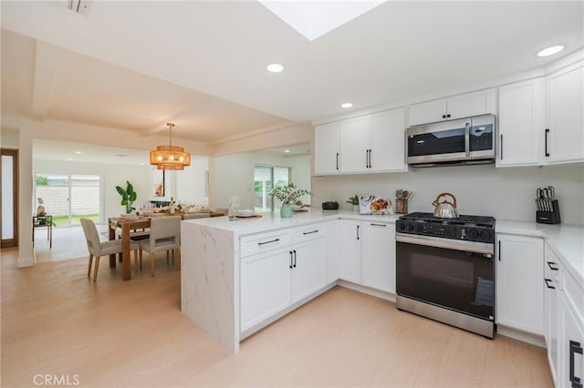 1304 Walling Ave, Brea, CA 92821 - kitchen featuring stainless steel microwave, gas stove, light wood-style flooring, a peninsula, and white cabinetry
