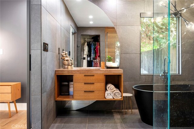 3066 Claret Cir, Atwater, CA 95301 - bathroom featuring a freestanding tub, vanity, and tile walls